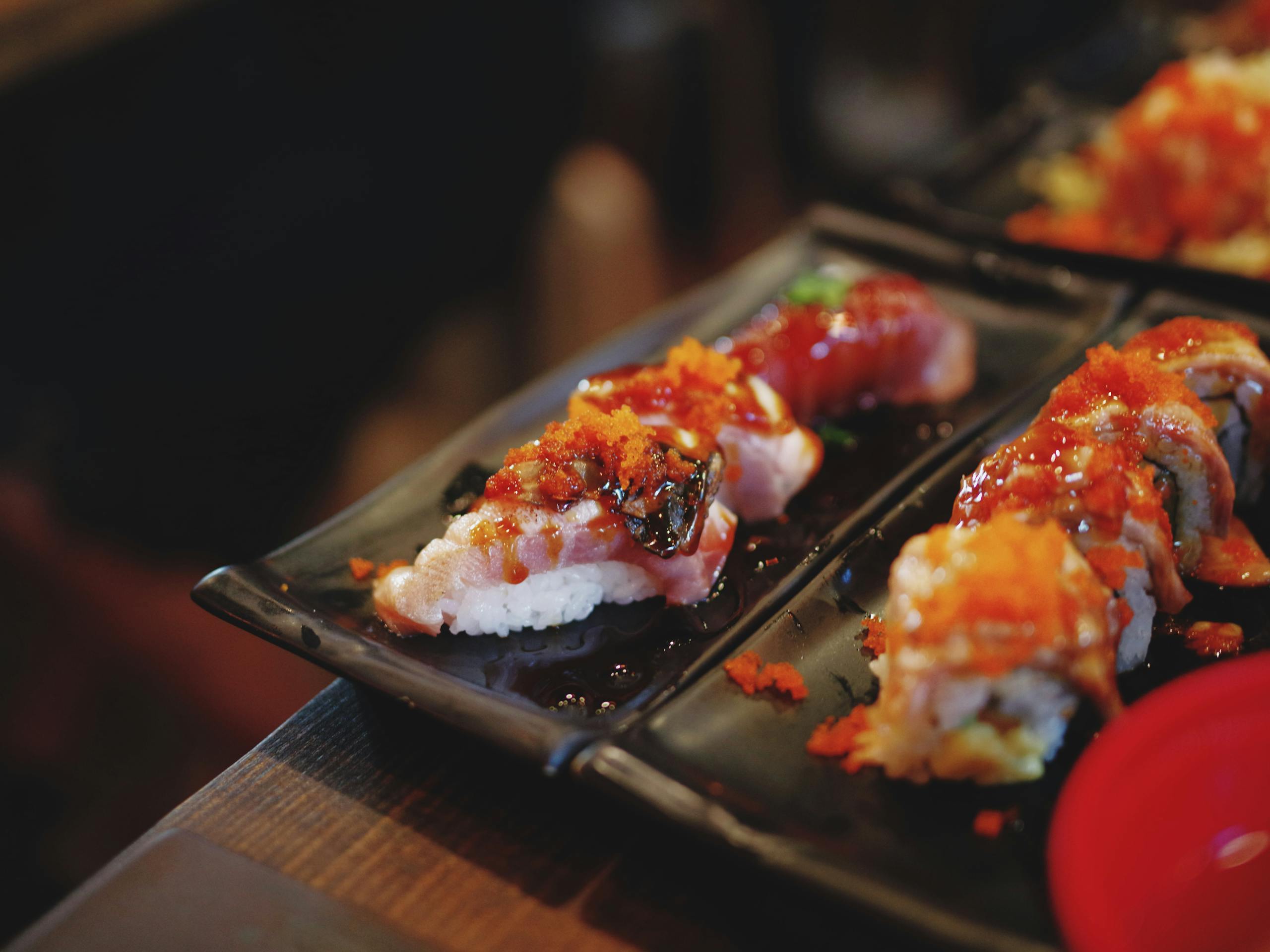 Appetizing sushi rolls with toppings served on a black plate, showcasing vibrant colors.